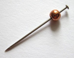 Push a sewing pin through the hole of a bead