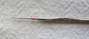 this tiny crochet hook fits through the hole of the bead 