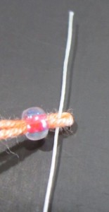 Bead placed on yarn loop of live stitch