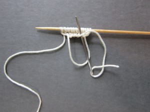 Pulling yarn tail through lower loop of next cast on stitch